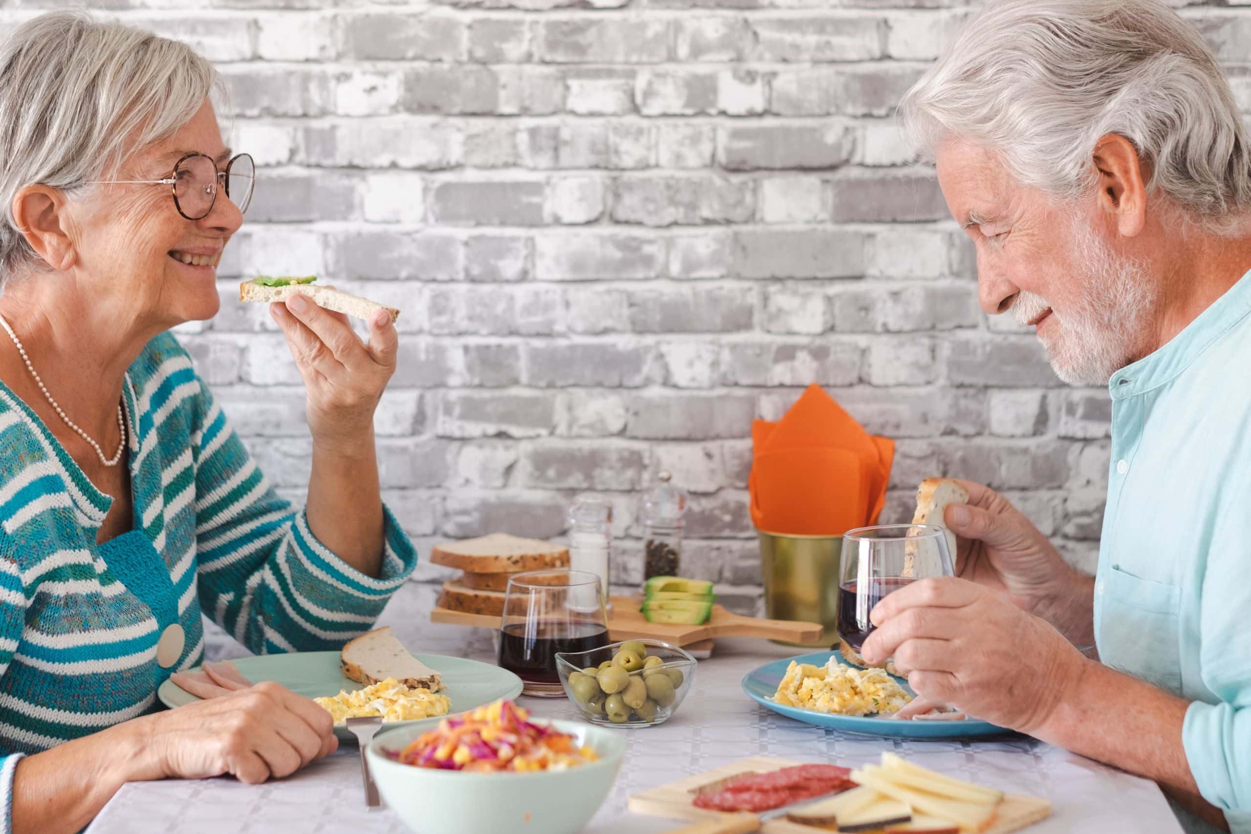 The elderly couple is stress-free as they have taken the teeth whitening session, showcasing their white teeth and enjoying their meal with a sip of wine.