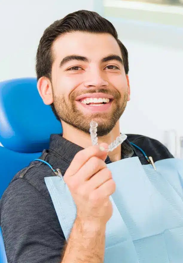Smiling patient holding clear aligners at Darley Dental Care